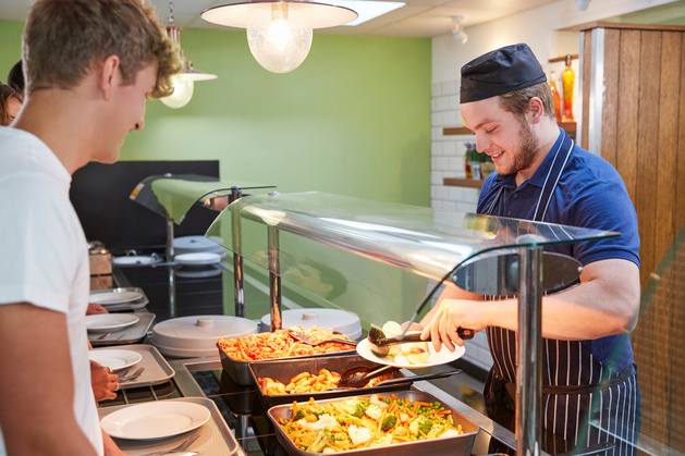 Photo of teenager being served food in a canteen.